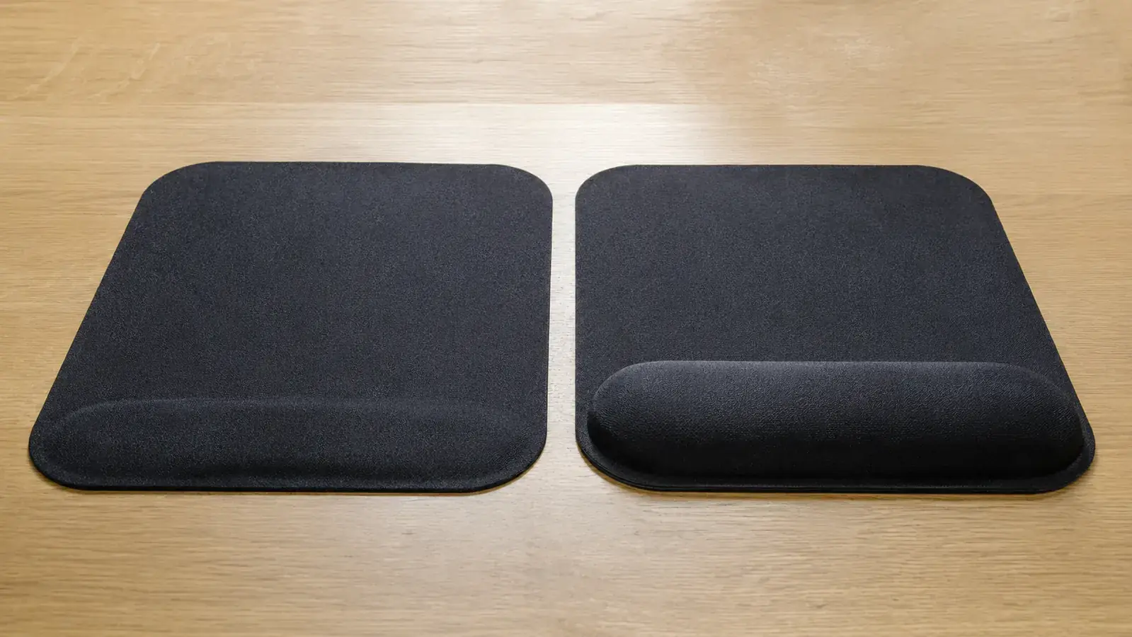 Two mouse pads on a desk, one showing visible gel compression after long use and one newer pad with the cushion still firm
