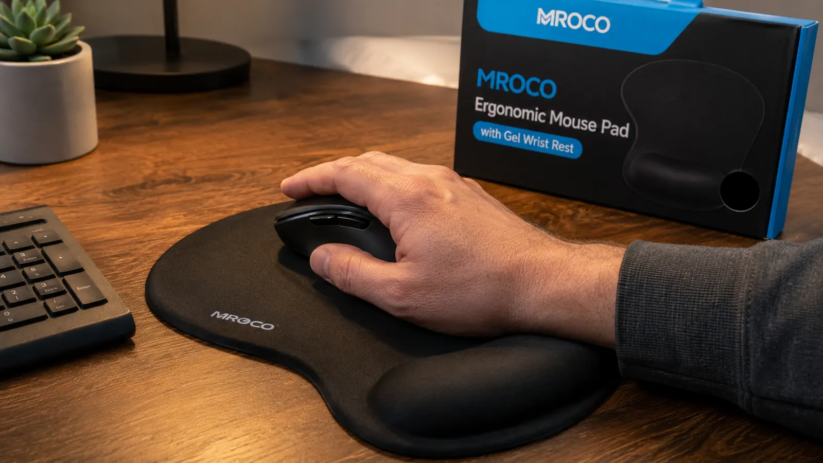 Right hand resting on an MROCO gel wrist rest while using a computer mouse on a black mouse pad